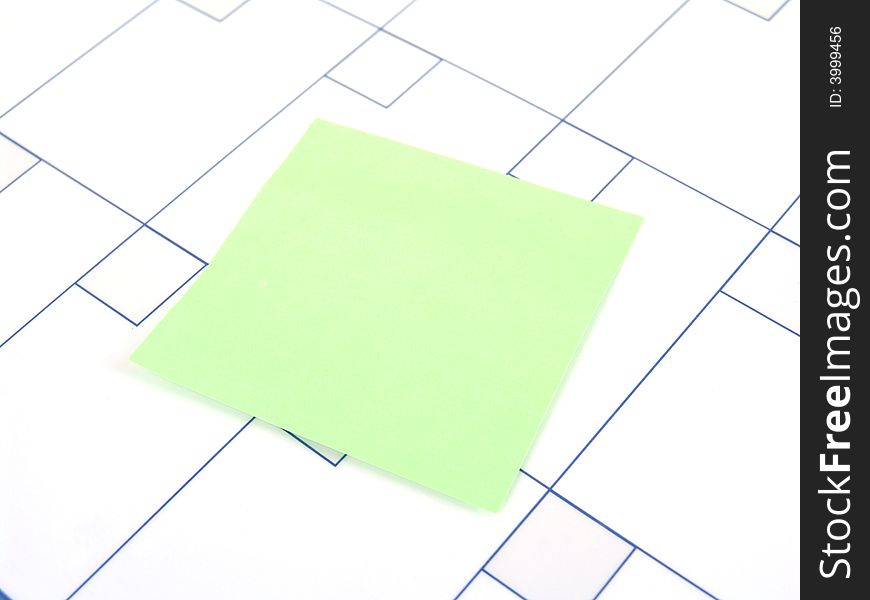 Green sticky note on surface of blank calendar