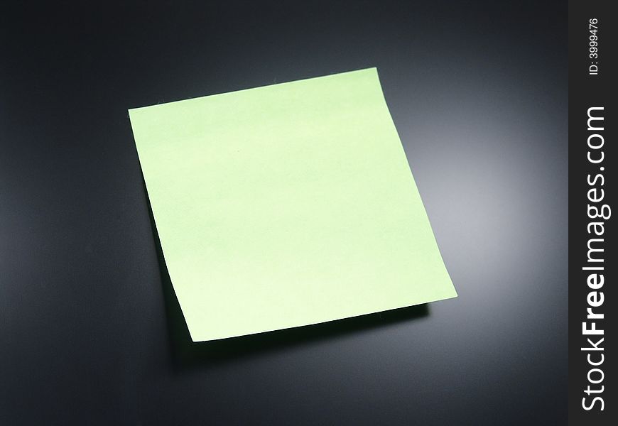Green sticky note on screen of computer with accent lighting