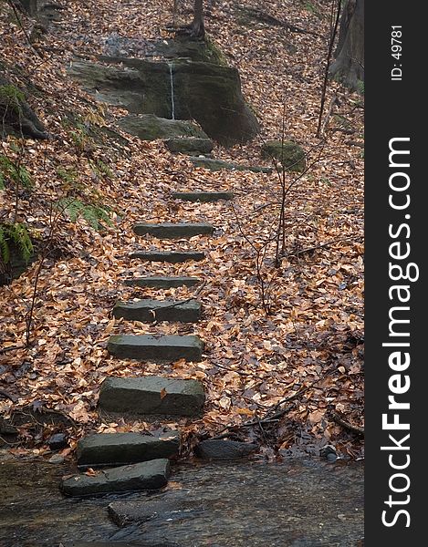 A set of stones makes a stairway leading to a small spring falling over a rock. A set of stones makes a stairway leading to a small spring falling over a rock.