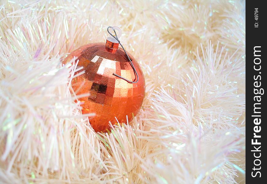A shiny bulb sitting in a pile of garland. A shiny bulb sitting in a pile of garland.