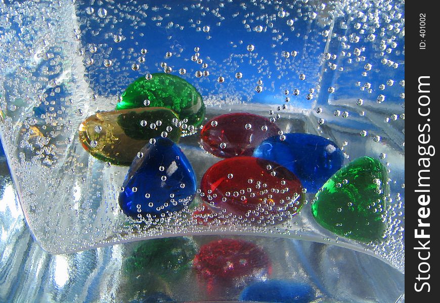 Small glass stones in a vase filled by the mineral water. Background. Small glass stones in a vase filled by the mineral water. Background