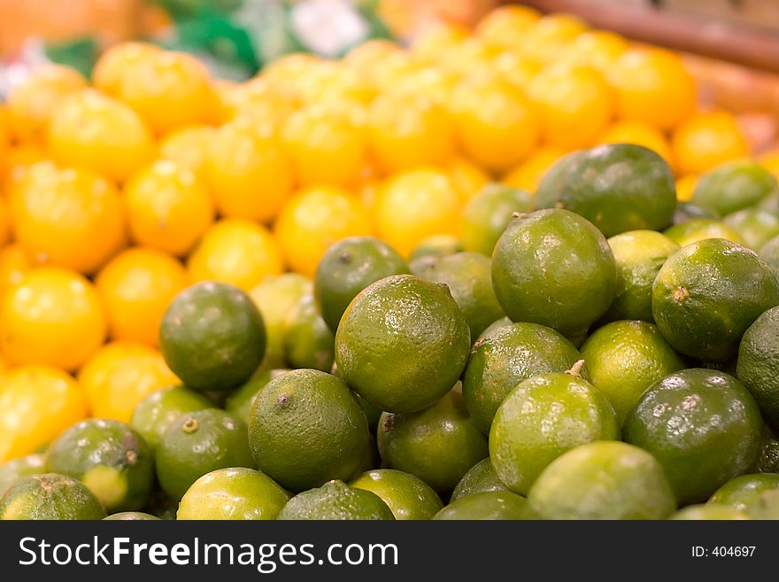 A pile of limes in focus against a blurred background of lemons. Shot at the local grocery store. A pile of limes in focus against a blurred background of lemons. Shot at the local grocery store.
