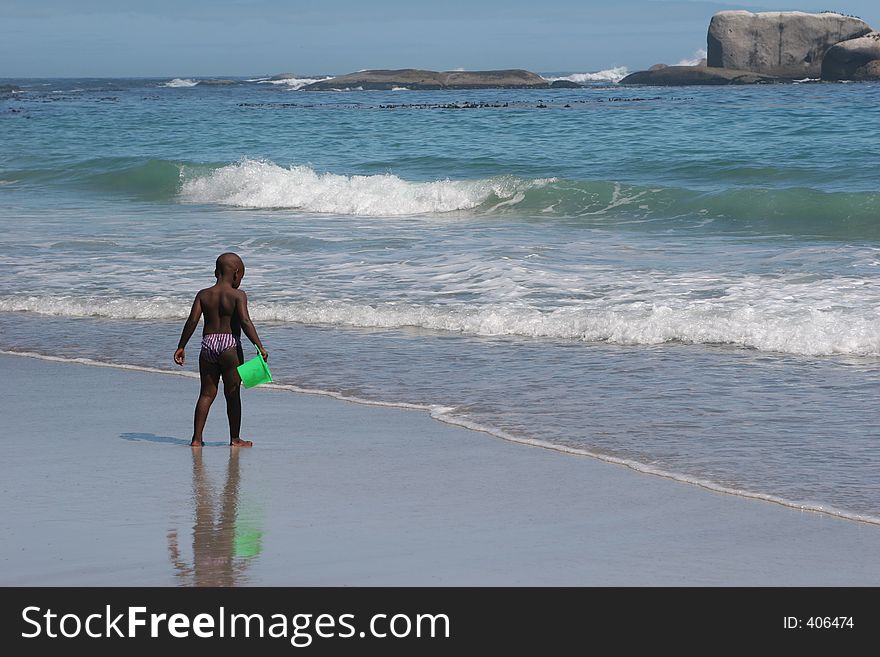 Clifton beach, South Africa,boy with a green bucket in his hand. Clifton beach, South Africa,boy with a green bucket in his hand