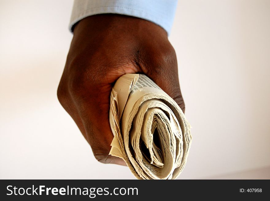 This is an image of a newspaper, folded and held by a black person. This is an image of a newspaper, folded and held by a black person