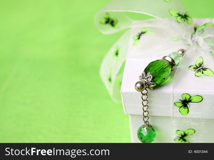 White gift box with green decorations and a crystal pin. White gift box with green decorations and a crystal pin