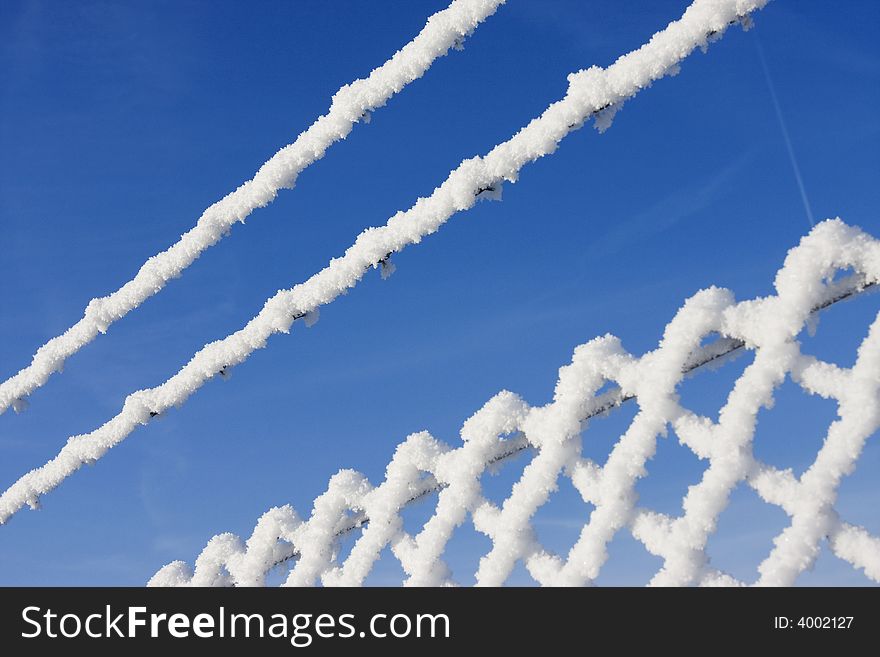 Snow fence in winter landscape with bright blue sky in background