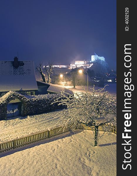 Kufstein town (Austria, Alps) at night, landscape view with distant fortifications and a countryside house in the foreground. Kufstein town (Austria, Alps) at night, landscape view with distant fortifications and a countryside house in the foreground