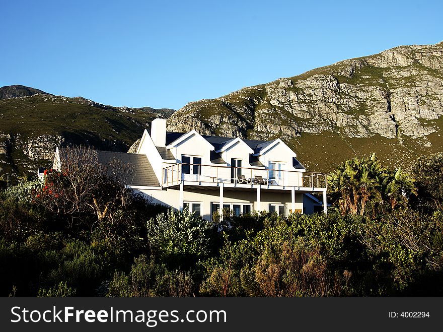 Beautiful white holiday house in the bush with some rocky mountains in the back ground