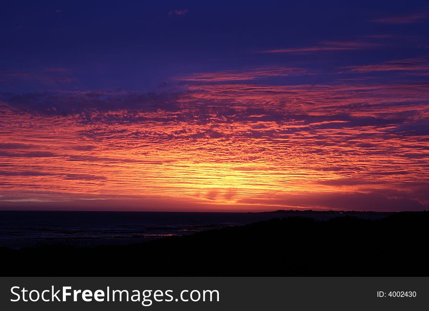 Beautiful sunset by the sea with colourful fluffy clouds