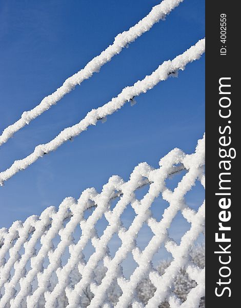 Snow fence in winter landscape with bright blue sky in background