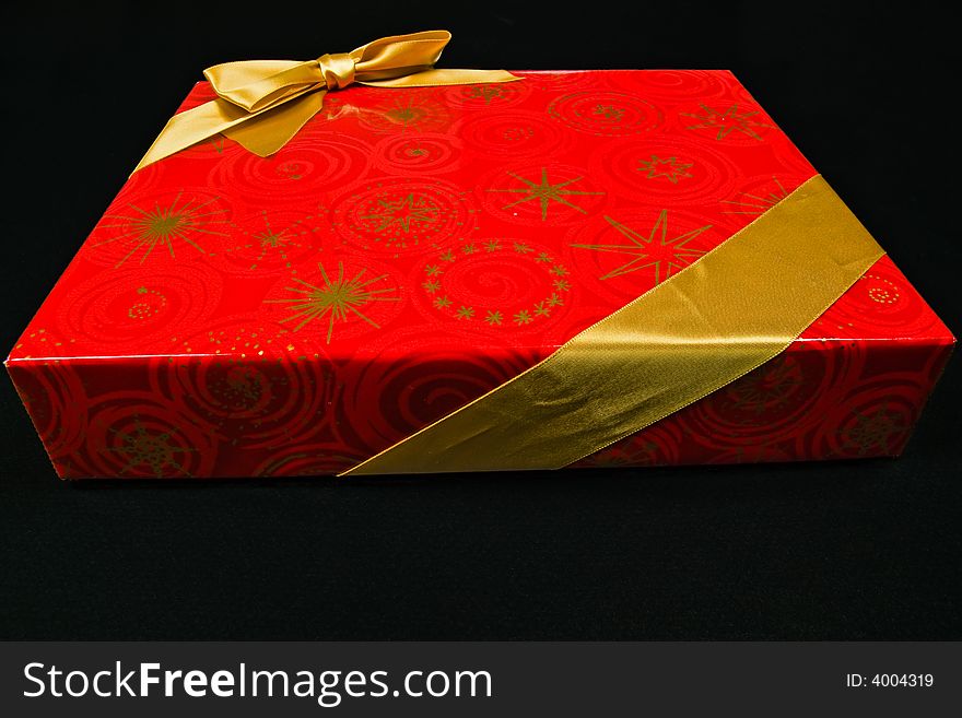 Chocolate candy in red gift box with golden ribbon - isolated on black