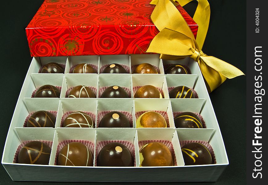 Chocolate candy in red gift box with golden ribbon - isolated on black