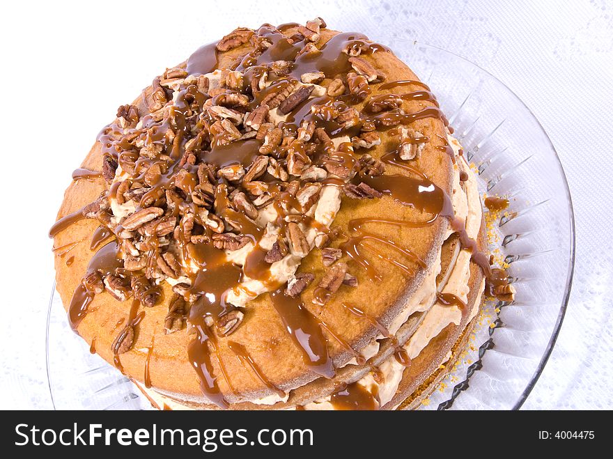 Sweet pumpkin cake dessert with cream filling and pecans on top drizzled with caramel topping on clear plate. Sweet pumpkin cake dessert with cream filling and pecans on top drizzled with caramel topping on clear plate