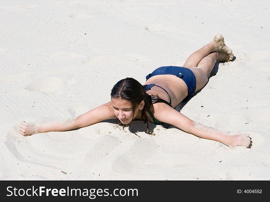 Girl lays on the sunny sand beach, warming up on hot sand after long swimming