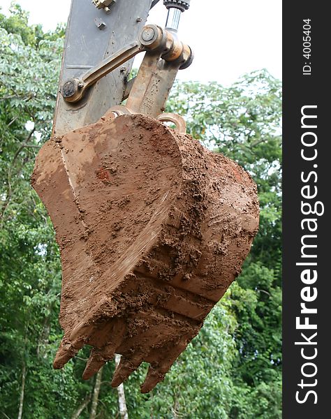 A giant shovel on heavy machinery. It is covered in mud. A giant shovel on heavy machinery. It is covered in mud