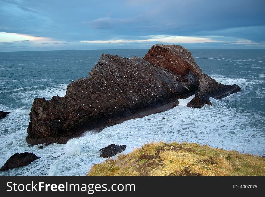 Bow Fiddle Rock, Portknockie, Scotland, U.K. Bow Fiddle Rock is a natural sea arch near Portknockie on the north-eastern coast of Scotland. It is so called because it resembles the tip of a fiddle bow. It is composed of Quartzite, a metamorphic rock which was originally quartz sandstone. . Bow Fiddle Rock, Portknockie, Scotland, U.K. Bow Fiddle Rock is a natural sea arch near Portknockie on the north-eastern coast of Scotland. It is so called because it resembles the tip of a fiddle bow. It is composed of Quartzite, a metamorphic rock which was originally quartz sandstone.