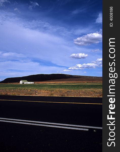 View of a field accross the South African road to the Karoo Desert with Clouds and Sky. View of a field accross the South African road to the Karoo Desert with Clouds and Sky