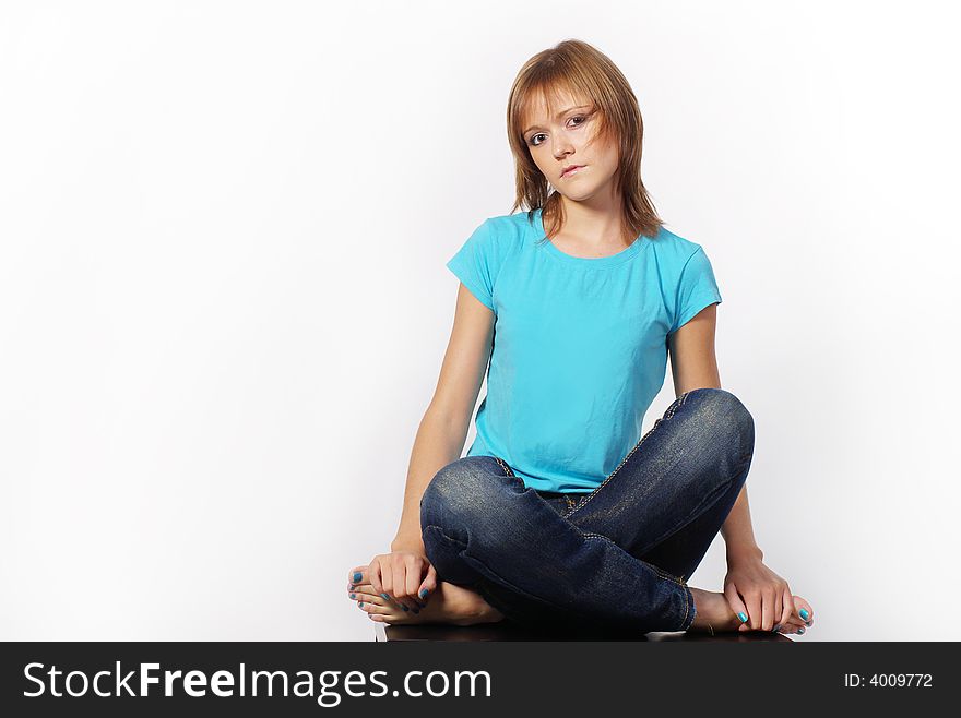 The girl sits on a table having crossed legs