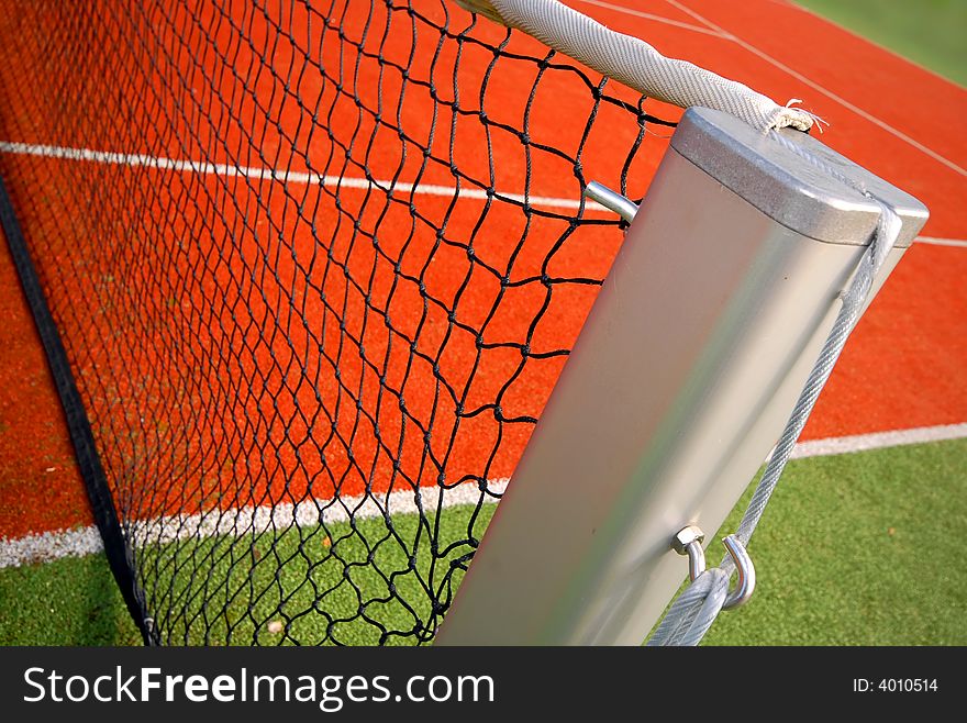 Tennis court with emphasis on the pole of the net