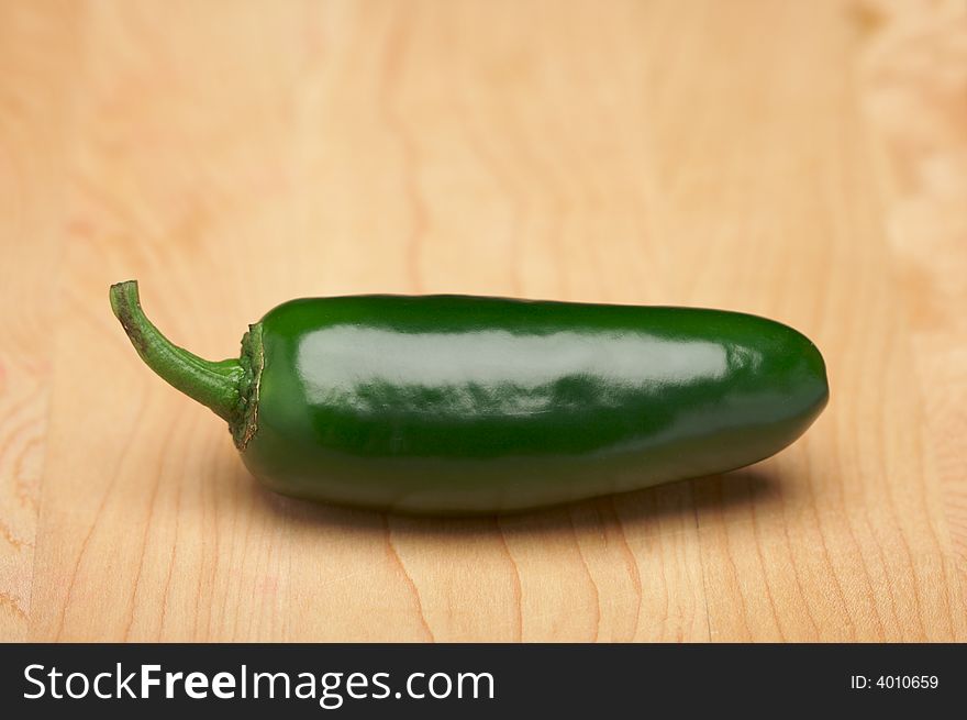 Hot Green Chili Pepper on a Wood Cutting Board - Room for Copy at the Top. Hot Green Chili Pepper on a Wood Cutting Board - Room for Copy at the Top.