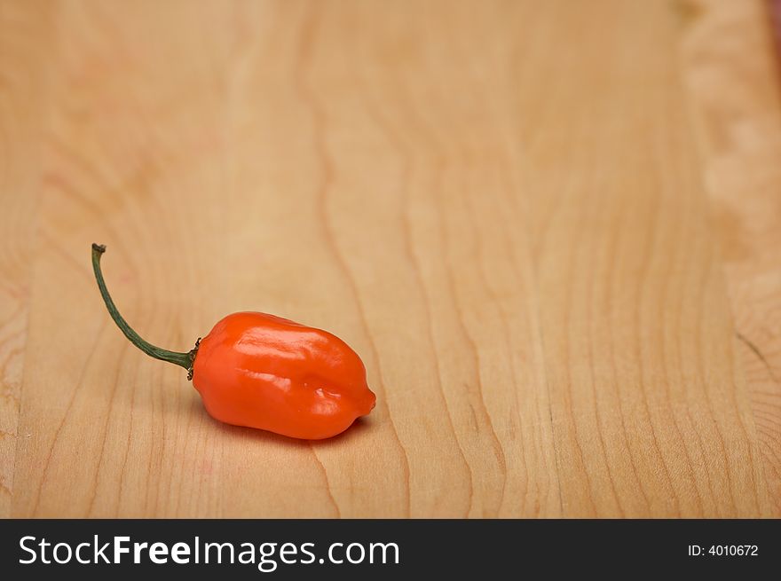 Orange Chili Pepper on a Wood Cutting Board. Room for Copy.