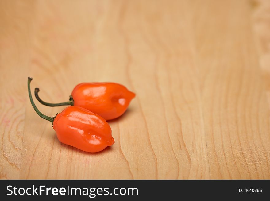 Orange Chili Peppers on a Wood Cutting Board. Room for Copy.