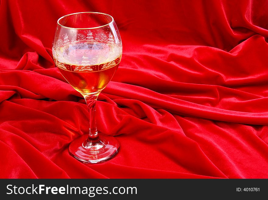 Golden wine in glass on red velvet. Golden wine in glass on red velvet