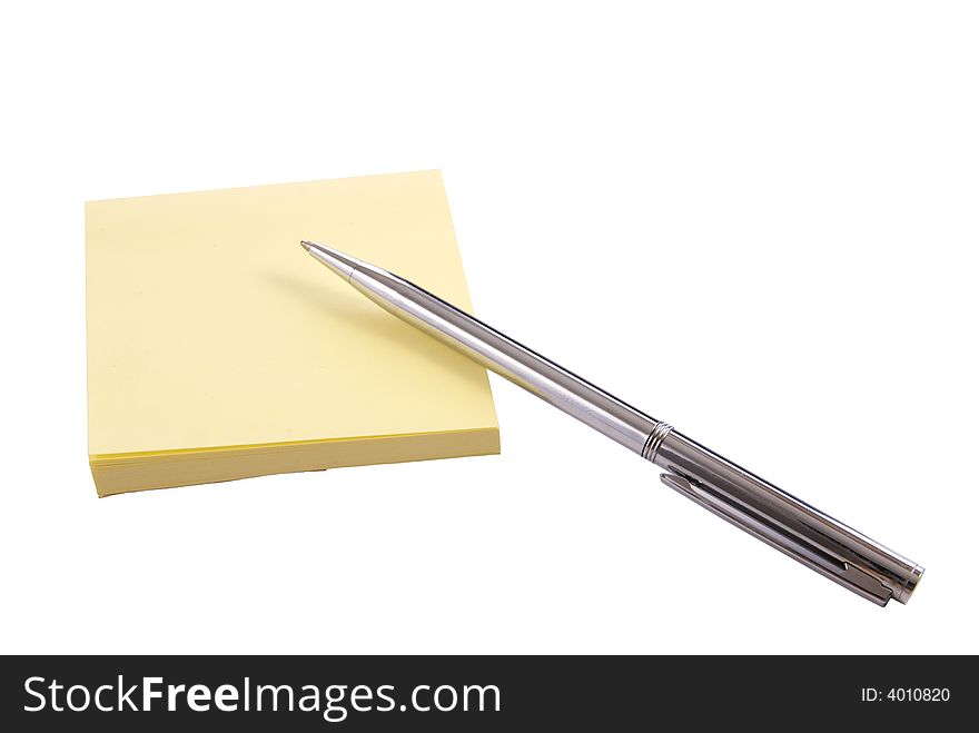 Isolated yellow notepaper pad with silver pen on white background. Isolated yellow notepaper pad with silver pen on white background