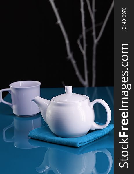 A modern table setting with a teapot and cup. A modern table setting with a teapot and cup