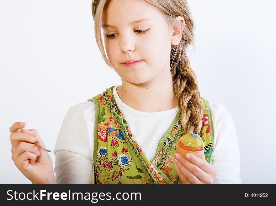 Studio portrait of a young blond girl who is painting eggs for easter. Studio portrait of a young blond girl who is painting eggs for easter