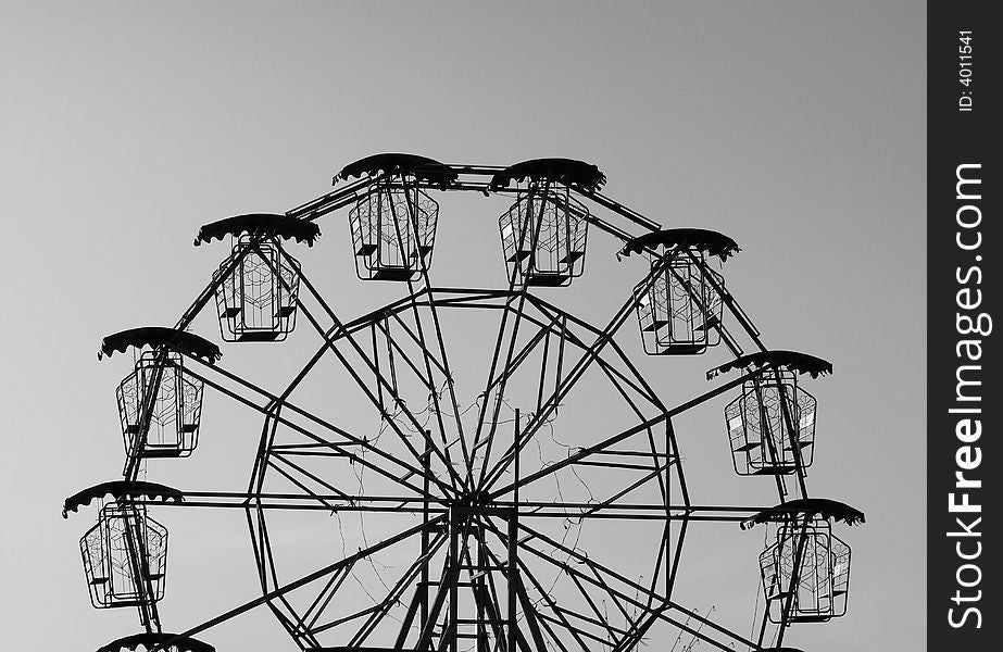 Silhouette of a small ferris wheel. Black and white photo.