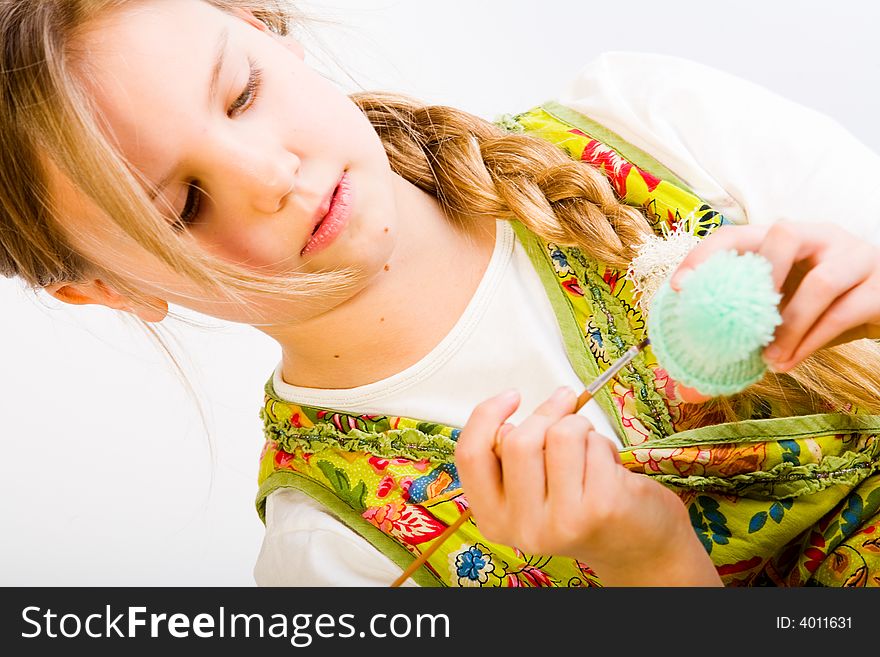 Studio portrait of a young blond girl who is concentrated on painting an egg. Studio portrait of a young blond girl who is concentrated on painting an egg