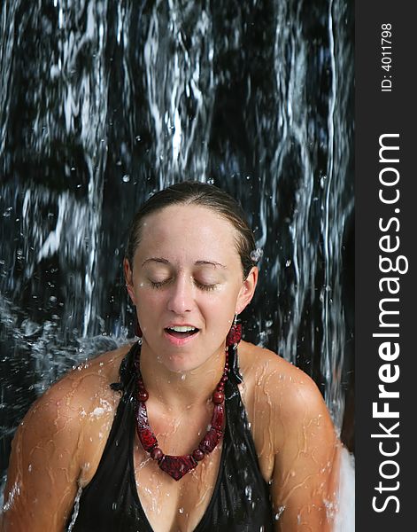 A young woman relaxes under a waterfall at a five star spa in Costa Rica. A young woman relaxes under a waterfall at a five star spa in Costa Rica
