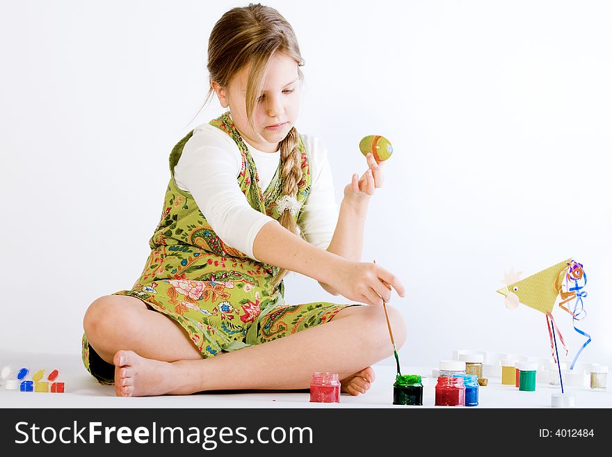 Studio portrait of a young blond girl who is playing with paint and eggs for easter. Studio portrait of a young blond girl who is playing with paint and eggs for easter