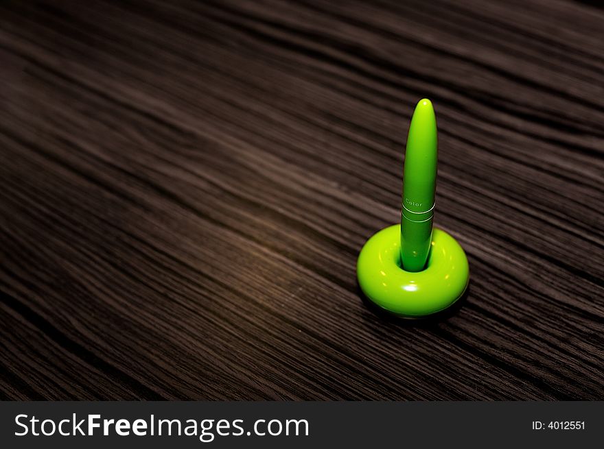 A ball point pen on the desk. green - chilly green. ready to be used for your notes. the donut holder adds some organic form to the writing tool. A ball point pen on the desk. green - chilly green. ready to be used for your notes. the donut holder adds some organic form to the writing tool