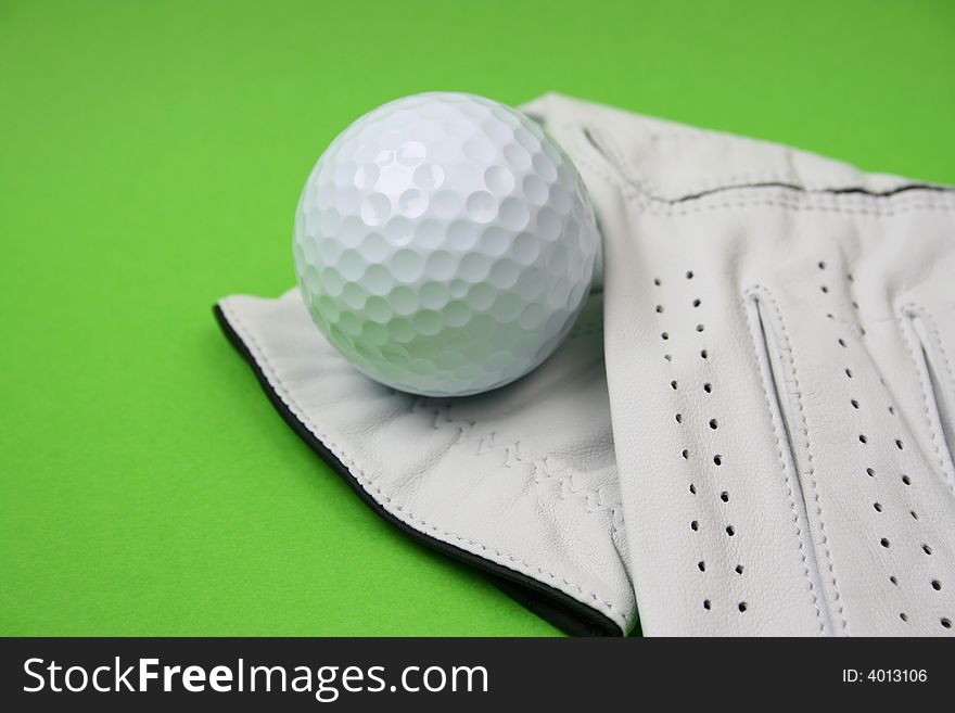 Golf glove and ball on a green background