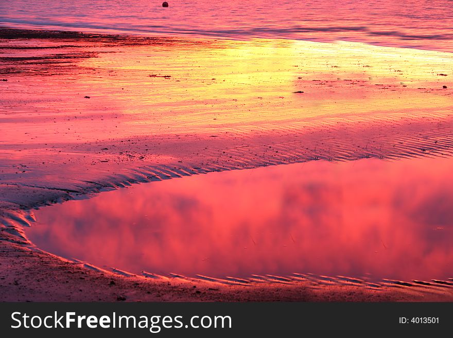 Sunset reflected in pool of water on beach. Sunset reflected in pool of water on beach