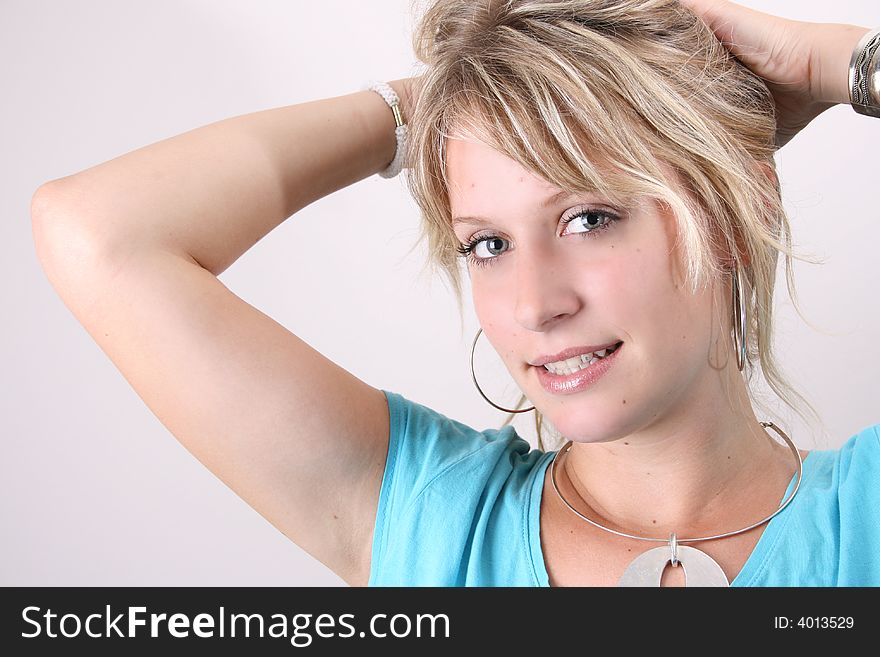 Blonde Female model taking up her hair to tie with a hair band. Blonde Female model taking up her hair to tie with a hair band