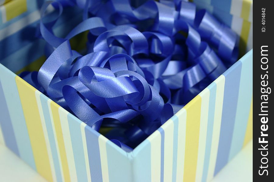 A striped box full of curly blue ribbon. A striped box full of curly blue ribbon.