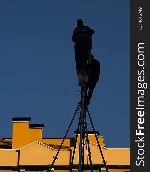 Silhouette of two technician working on the roof
