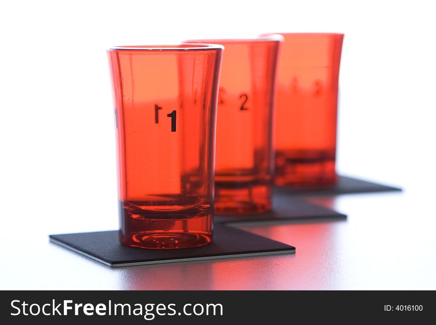 Three red glass numbered glasses on black supports