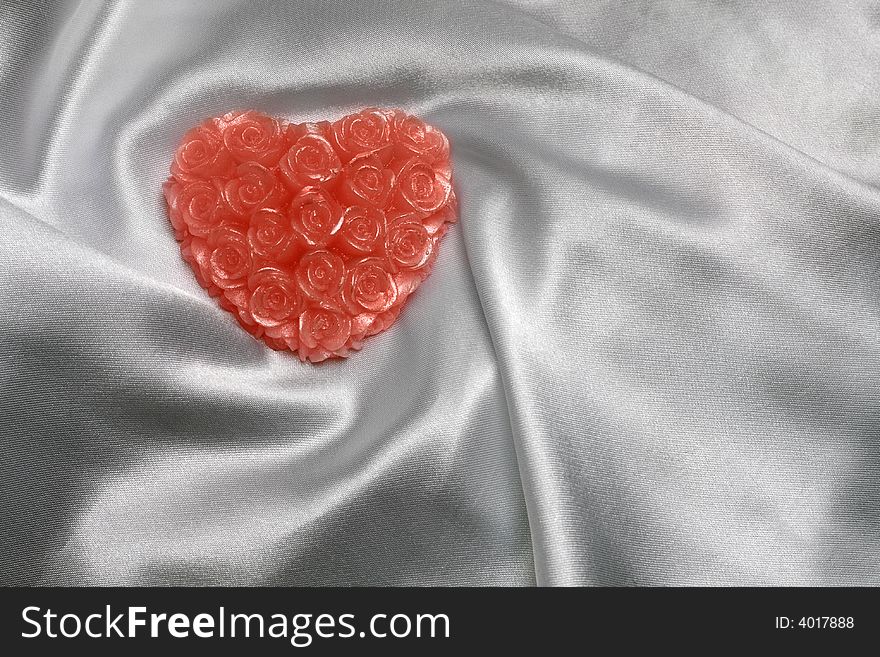 Heart-shaped candle on white satin