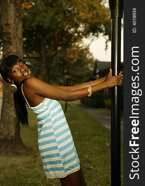African american girl with happy expression swinging on light pole. African american girl with happy expression swinging on light pole