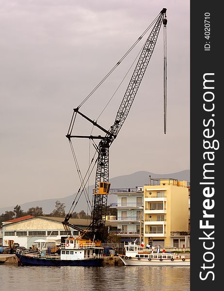 Image shows an industrial crane over a Mediterranean port