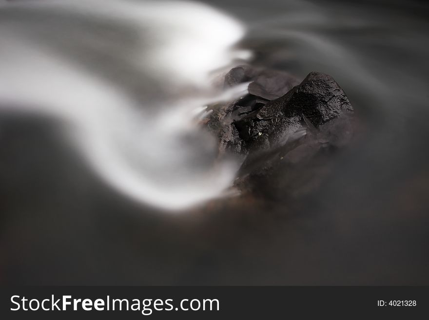 An Abstract image of water flowing around a rock. An Abstract image of water flowing around a rock.