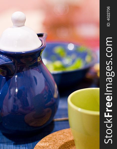 A blue teapot and a yellow cup. A blue teapot and a yellow cup.