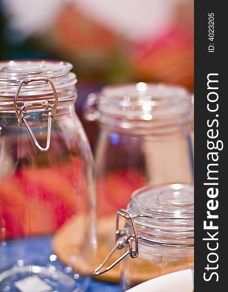 Closeup of some empty glass jars on a coloured background.