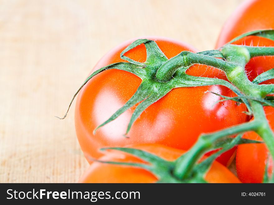 Juicy red tomatoes on the vine on a wooden background. Juicy red tomatoes on the vine on a wooden background
