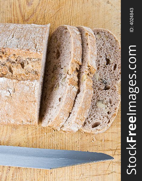 A fresh bread loaf with a knife on a wooden board