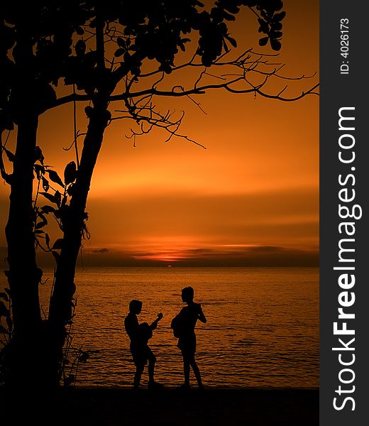 Some boys playing guitar at the beach during sunset. Some boys playing guitar at the beach during sunset